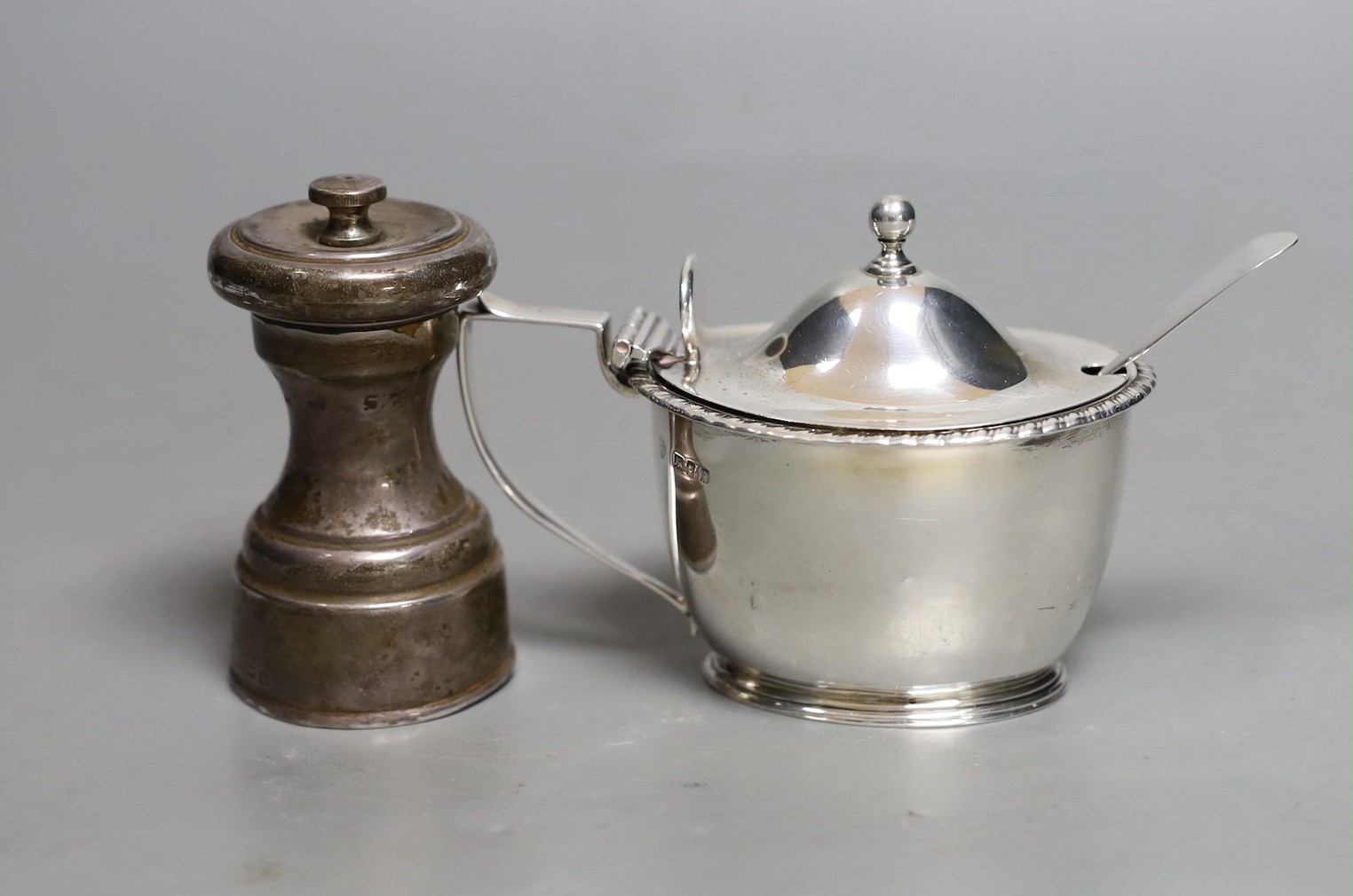 A George V silver mounted pepper mill, Birmingham, 1911, 80mm and a similar silver mustard pot.